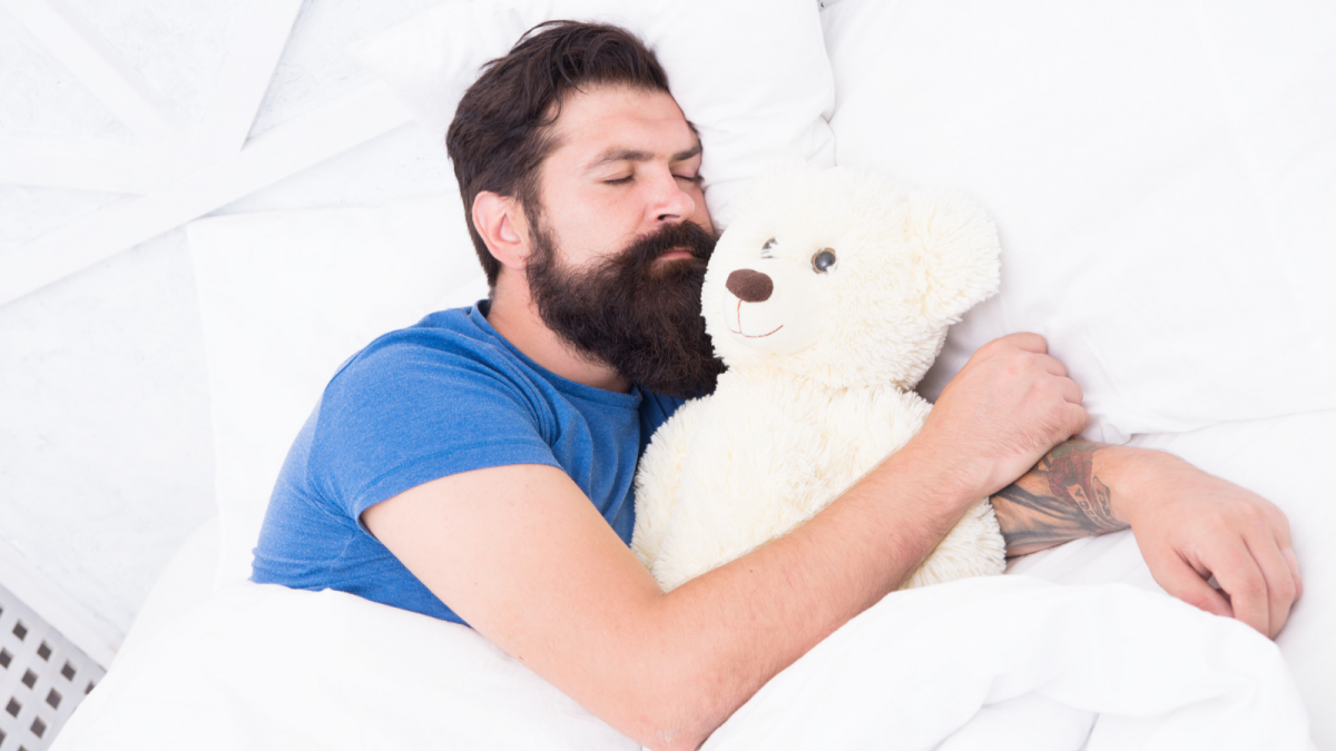 Bartträger im Bett mit Teddybär