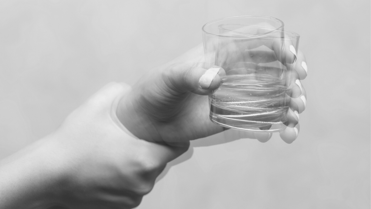 eine zitternde Hand hält ein Wasserglas